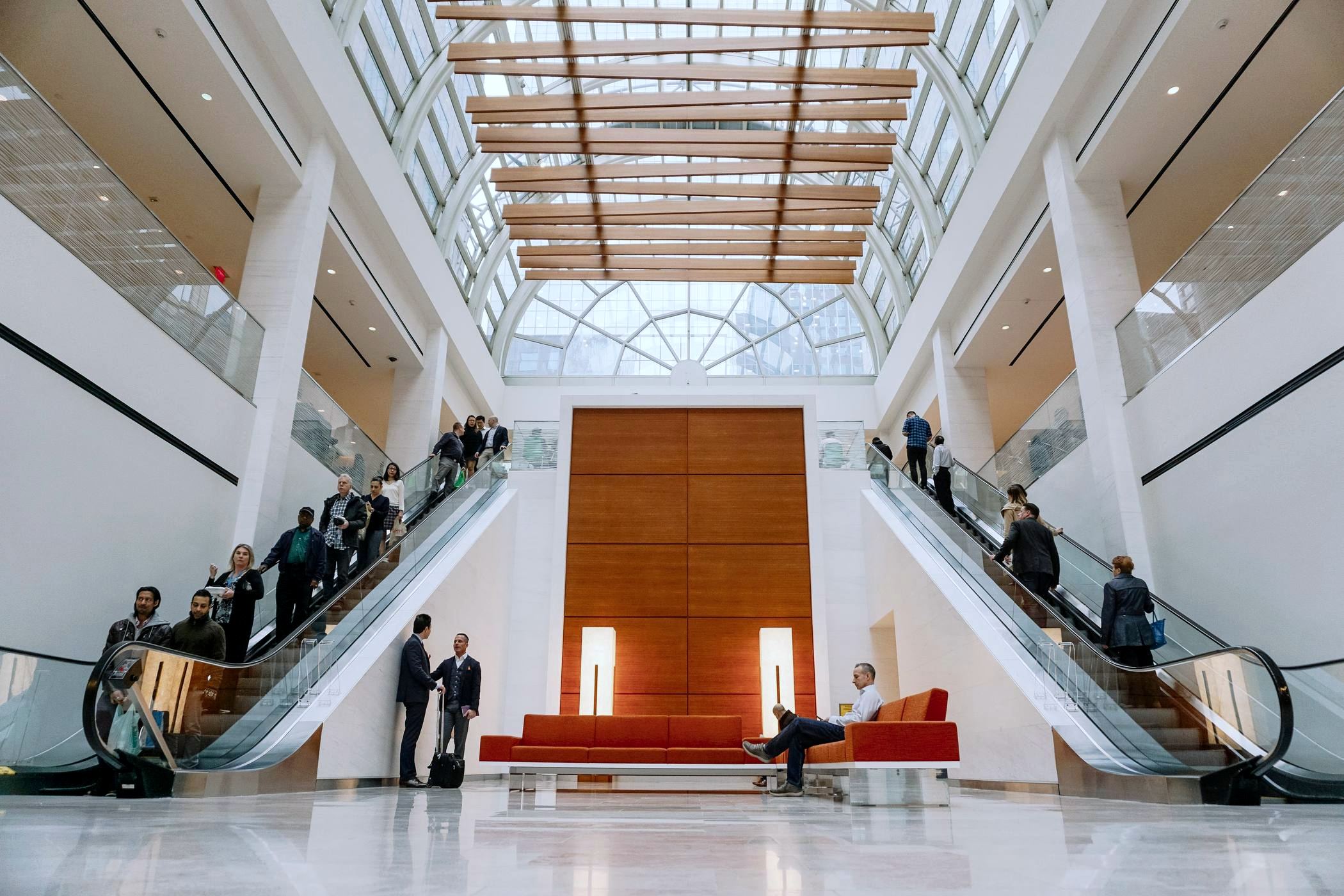 A tall stone and wood atrium lobby with professionals meeting
