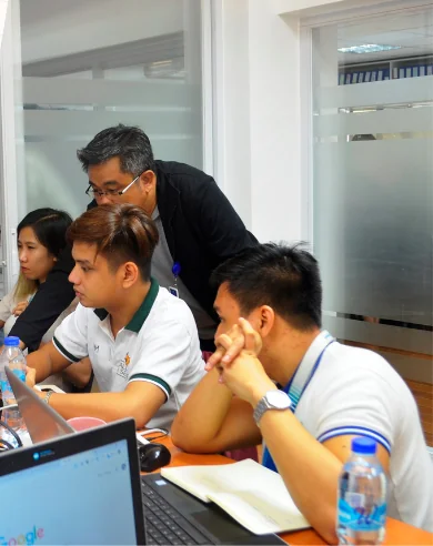 An instructor guiding PCHRD-DOST trainees at their laptops