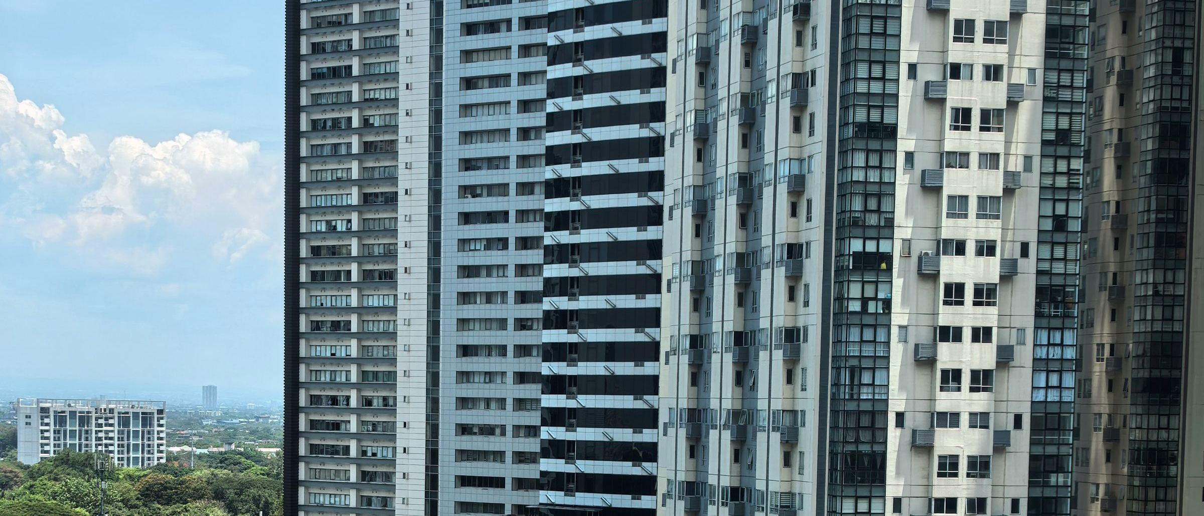 High-rise towers above a tree-lined avenue in Makati, Metro Manila